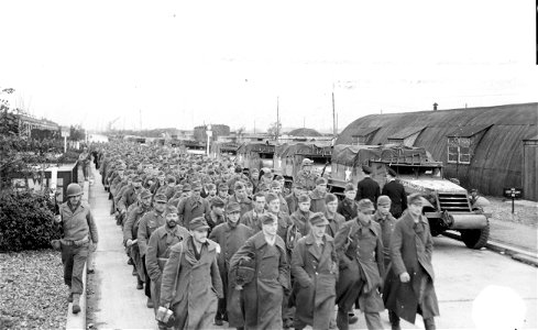 SC 195734 - Nazi prisoners are seen marching along a street in a southern English port as American armored vehicles await transport to France. 13 October, 1944. photo