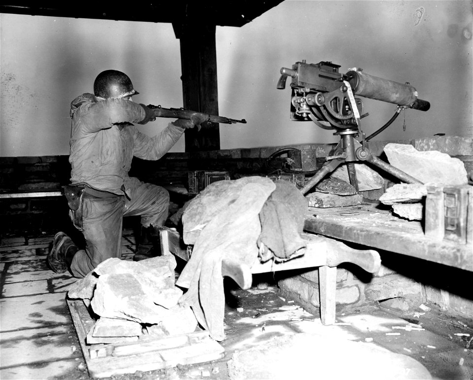 SC 364287 - Pfc. Al Shires, Huntington, W. Va., fires a captured German rifle at enemy positions on the east bank of the Urft River. 6 February, 1945.