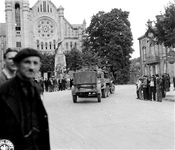 French civilians gather to watch the American trucks pass through the town square in Bar-le-Duc, France. Note the French and Russian flags flying from the World War I monument. 1 September, 1944.