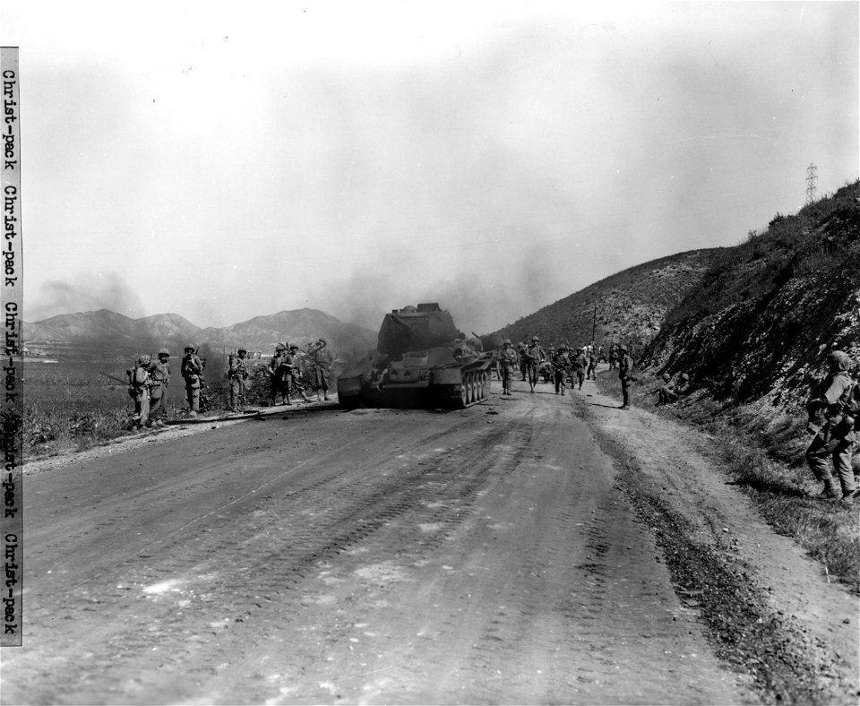 SC 349017 - North Korean T-34 tank knocked out by elements of the 1st Marine Div. is given a look over by Marines on their way to reinforce front lines northeast of Inchon, Korea. 17 September, 1950. photo