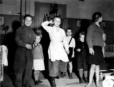 SC 404998 - Inside the St. Jacques Displaced Persons Cap, Knutange, Fr., the children under the direction of French Red Cross woman, have a room of their own where they can dance and play as they wish. photo
