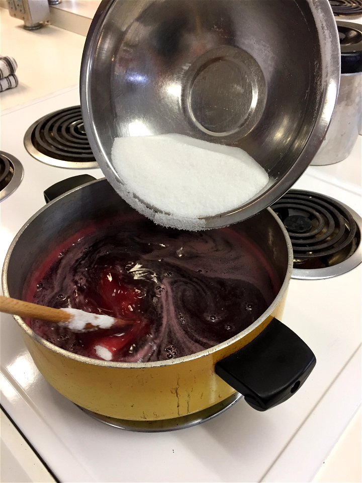 Stirring sugar into heated grape juice photo