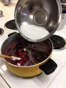 Stirring sugar into heated grape juice