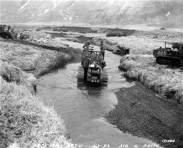 SC 171524 - After supply trucks had bogged down in the coastal mud the tractors found that the hard bed of this stream afforded good traction. Attu, Aleutians. 1943. photo
