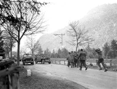 SC 337283 - (409th Task Force photo series) German O.C.S. candidates half carry one of their wounded schoolmates, as other men hurry in having surrendered to a Task Force smashing over the Austrian border.