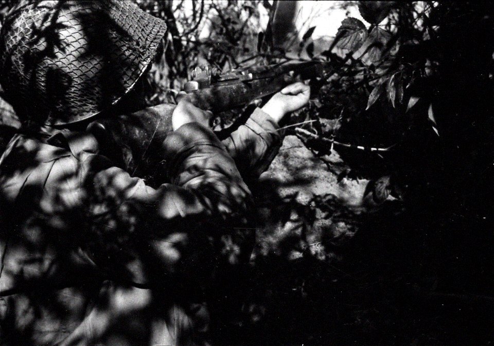 SC 364279 - Pfc. Calvin Stempien, Monroe, Mich., levels covering fire from his foxhole while members of his engineer unit construct a bridge over the Meurthe river, under enemy fire.
