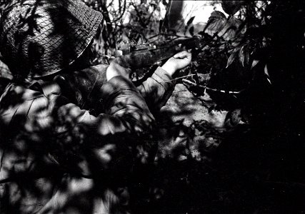 SC 364279 - Pfc. Calvin Stempien, Monroe, Mich., levels covering fire from his foxhole while members of his engineer unit construct a bridge over the Meurthe river, under enemy fire.