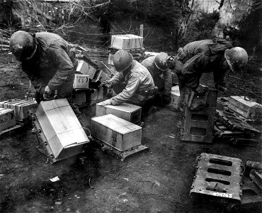 SC 374765 - Infantrymen of the 94th Division, 3rd U.S. Army, strap cases of "K" rations to rackboards, to be carried up to the front line. 25 February, 1945.