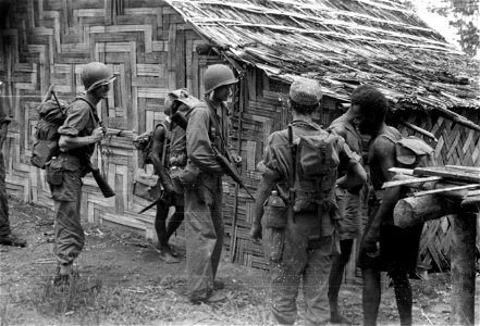 SC 374821 - L-R: S/Sgt. Wm. G. Baker, Oakland, Cal.; T/5 Wilson Cedars, Derry, La.; and back to camera, Smoky Johnson, Wooster, O., members of the 37th Recon Troop Patrol passing native hut at Karikakau village...