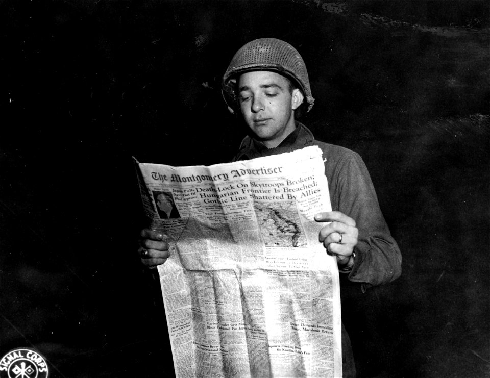 SC 396918 - 1st Lt. Gordon H. Schofield, 714 Winona Avenue, Montgomery, Alabama, glances through a copy of a hometown newspaper.