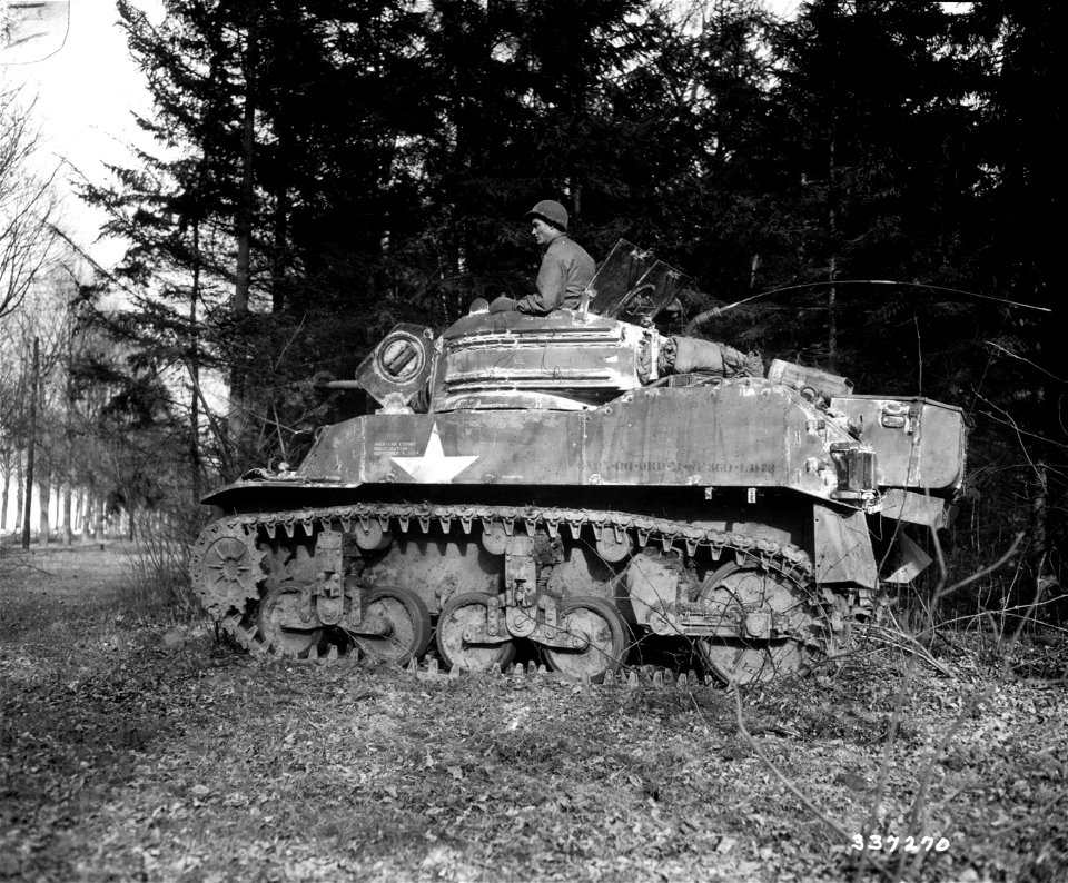 SC 337270 - Pfc. J. E. Barnes, Shannon, Miss., sits on his light tank under cover of pine trees, on the road to Krefeld, Germany.