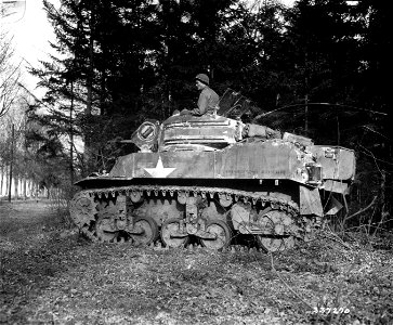 SC 337270 - Pfc. J. E. Barnes, Shannon, Miss., sits on his light tank under cover of pine trees, on the road to Krefeld, Germany.