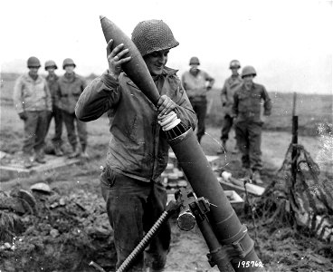 SC 195762 - Pvt. Harry Stockow, Canton, Ill., loads a captured German mortar (35 lb projectile). 29 October, 1944.
