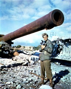 C-766 - Lt. Francis P. Mulhair, South Norwalk, Conn., who recently received a battlefield commission, stands in front of damaged coastal defense guns in the Italian-German proving grounds in Viareggio, Italy. photo