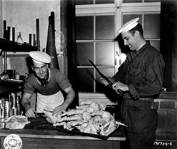 SC 195754-S - T/4 Frank F. Leichtman, left, of Bresho, S.D., cleans a batch of chickens while Mess Sgt. William L. Grounds, right, of Martinsville, Ind., sharpens a knife. photo