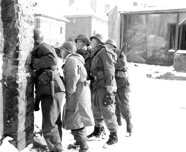 SC 199063-S - Lieut. Col. Porter, Commanding Officer of an infantry battalion, and his party, stand in the cover of a wall before dashing across a street in the Hagenau area, which is under enemy observation and small arms fire. photo