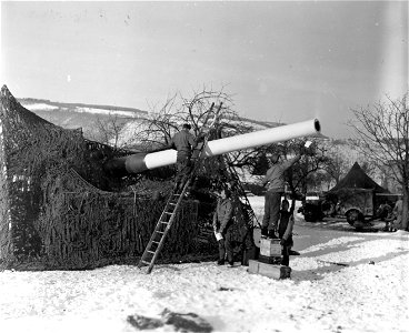 SC 374708 - Men of the 602nd Camouflage Bn. paint tube of 8 inch rifle to conceal it from enemy air observation. 17 January, 1945.