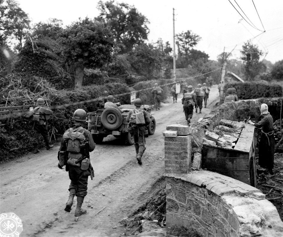 SC 270661 - An elderly French peasant watches members of an American motorized unit move past her farm northwest of St. Lo.