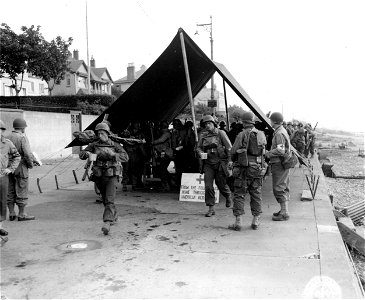 SC 329719 - Members of an American Ranger unit file quickly through a Red Cross canteen tent for their last "snack" of doughnuts and coffee before leaving an English harbor to strike the initial blow of the last act in the world's greatest conflict.