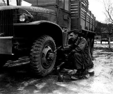 SC 374721 - The paint job on the wheel of this First Army truck is touched up by Pfc. Lawrence J. Morris, 3449 Marshall Road, Upper Darby, Pa., 83rd Quartermaster Depot, 83rd Infantry Division.