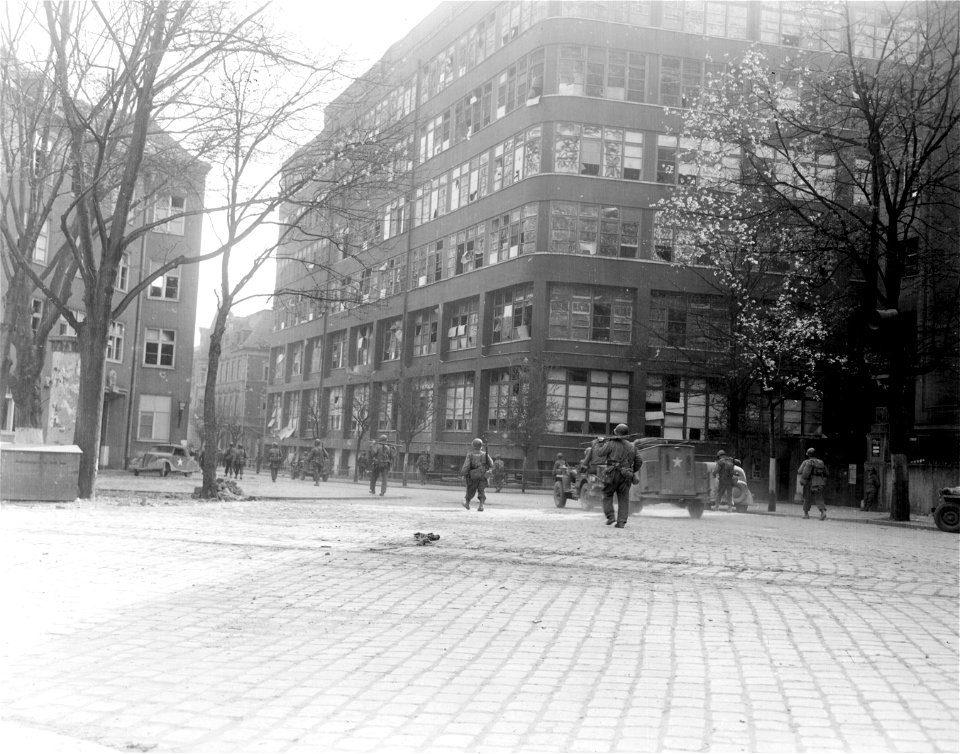 SC 335316 - Infantrymen of the 80th Division of Gen. Patton's Third Army passing the Carl Zeiss Lens and Camera Plant in newly-captured Jena, Germany. 15 April, 1945. photo