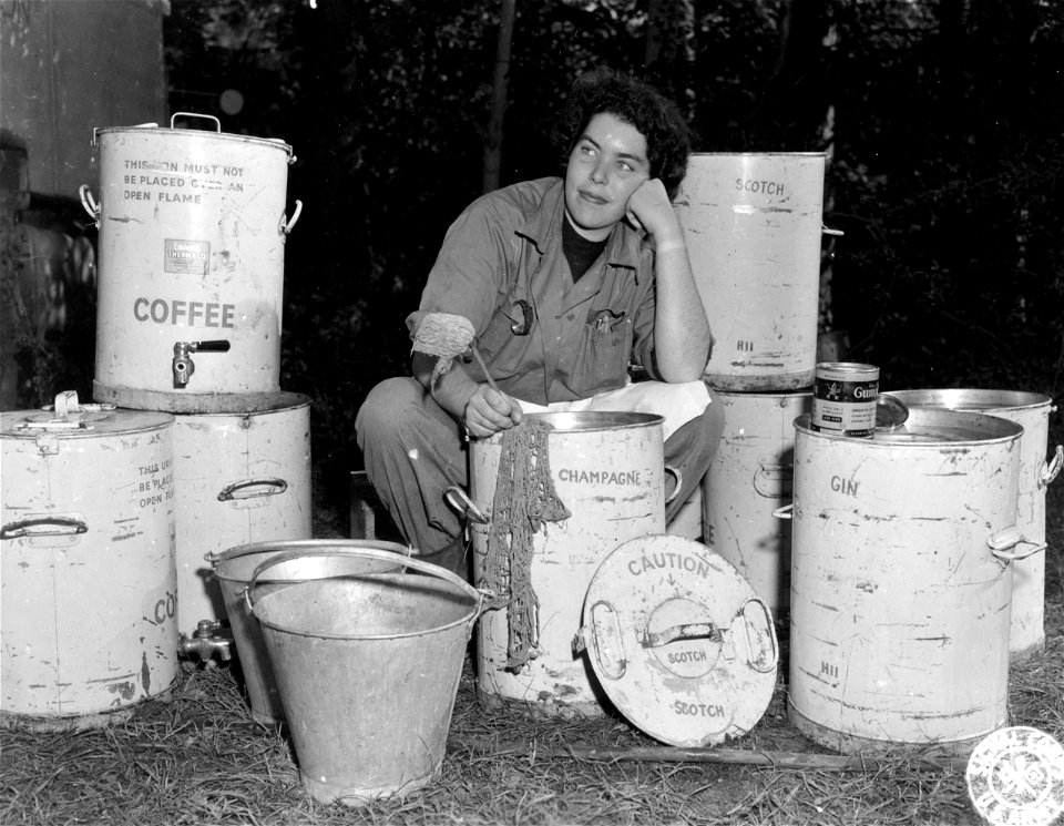 SC 195540 - Sally Reed, Durham, Mass., a Red Cross worker somewhere in France, does a bit of KP on the large containers about her--and she doesn't believe in signs for they're all coffee urns. 1 October, 1944.