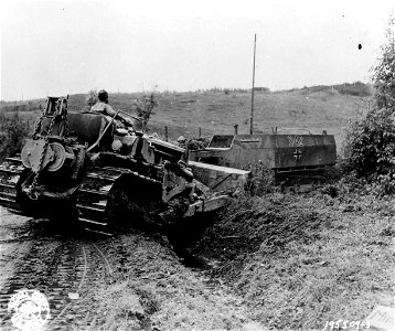 SC 195509-S - Out of the way! An engineer bulldozer shoves a knocked-out German halftrack from the road near Bruyeres, France. 24 October, 1944. photo
