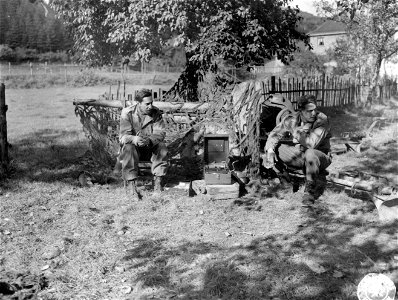 SC 195690 - Sitting in front of a 57mm anti-tank gun, these two U.S. infantrymen listen to swing music from portable phonograph during spare time on German front, near Zweifall, Germany. photo