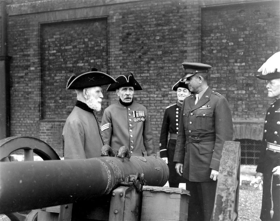 SC 329891 - Lt. Gen. Jacob L. Devers, C.G., ETO, while visiting the Royal Chelsea Hospital, listens to the pensioners explain an early Dutch gun. L-R: