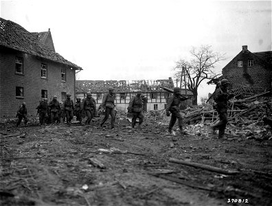 SC 270812 - Machine gunners of the 8th Division, U.S. First Army, advance through Binsfeld, Germany, in a new push on German positions. 26 February, 1945.