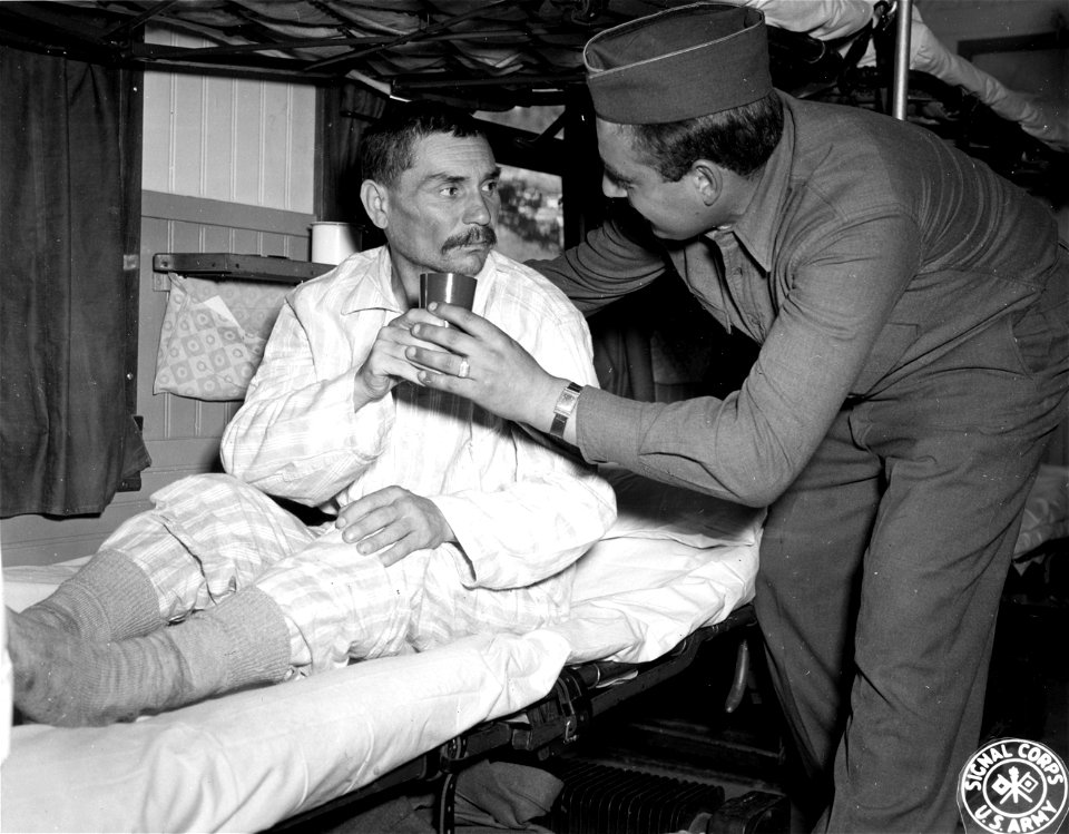 SC 405045 - Pfc. Rasquale Messano, of Hillside, N.J., gives a Russian patient a chocolate drink on a Swedish hospital train at Oslo, Norway. This train will repatriate him to Russia via Sweden.