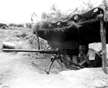 SC 348634 - An ROK soldier of the 15th Regt., 1st ROK Div., sights through his well-camouflaged .50 cal. machine gun at the North Korean enemy, north of Taegu. 18 September, 1950.