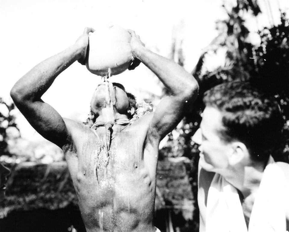 SC 171589 - A curious soldier watches a New Guinea native in the art of coconut drinking. Simemi, New Guinea. 25 December, 1942.