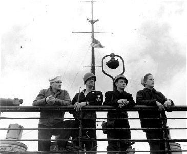SC 364338 - Two members of the USN security guard aboard inspect the surrounding harbour together with two members of the party directing the re-fitting.
