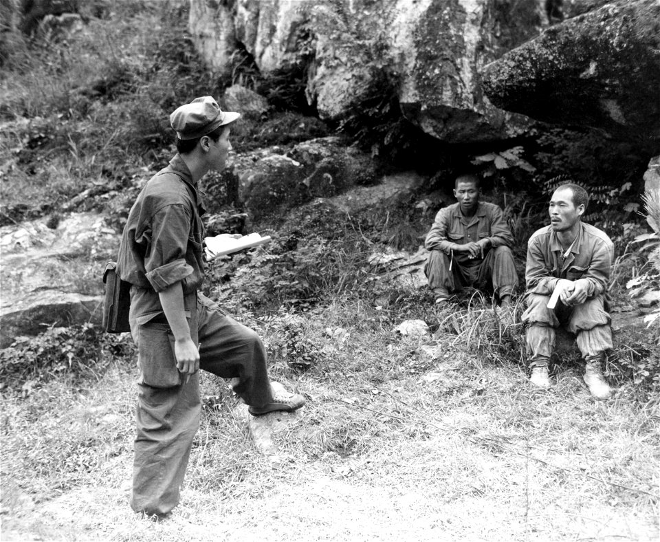 SC 348635 - An ROK interrogator questions two N. Korean prisoners who voluntarily surrendered to troops of the 11th Regt., 1st ROK Div. north of Taegu, Korea. 18 September, 1950.