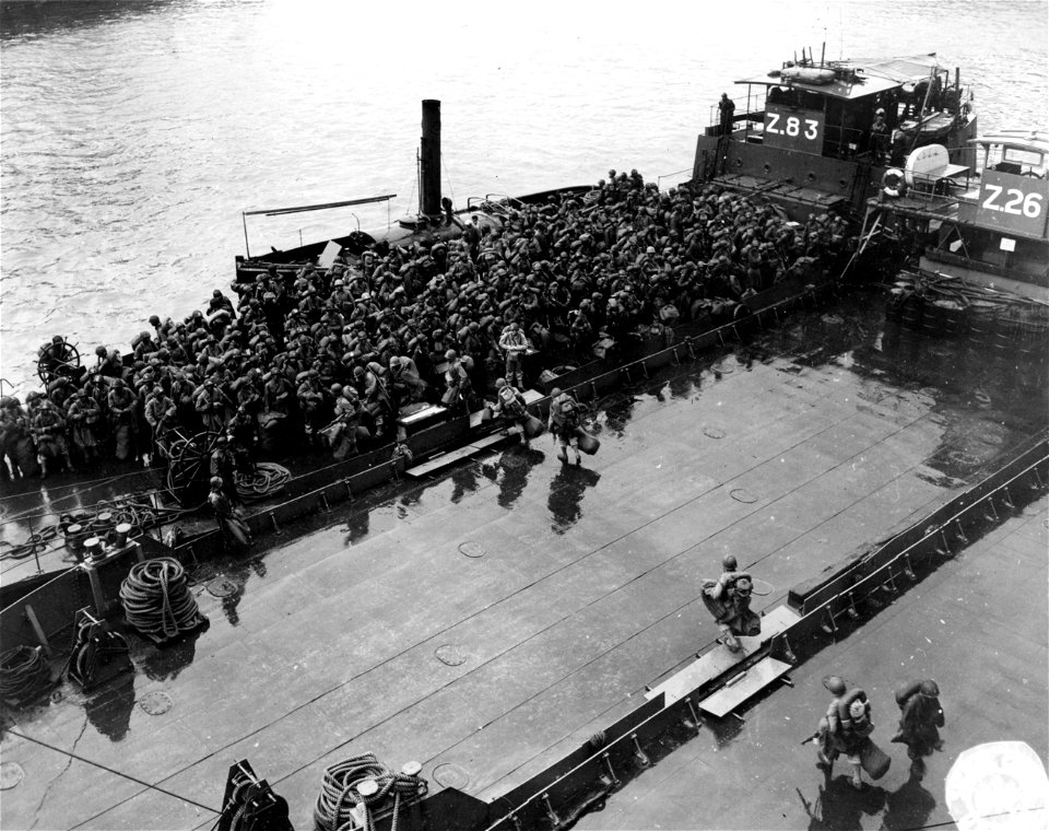 SC 195583-S - Heavily-laden American Negro troops walking across the decks of British "Zed Lighters" to be carried ashore. They came on the French troop ship "Columbie" from the United States. 6 October, 1944.