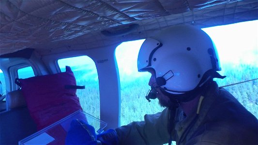 Crew Member Surveys Smokey Forest from a Helicopter