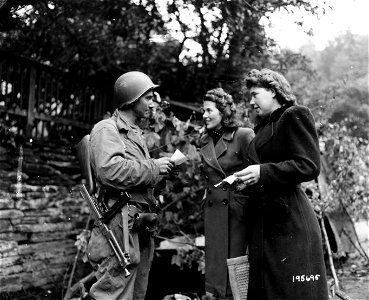 SC 195695 - Registration slips of these two German frauleins are checked by T/4 Nick Kellen, Woodstock, Mich., as they pass through the outskirts of Monschen, Germany. photo