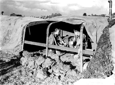 SC 195691 - GIs of the 3rd Armored Division use a truck-racked tarp as a shelter beside their foxhole near Stolberg, Germany.