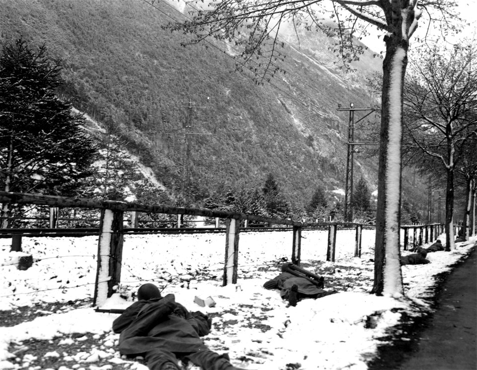 SC 337383 - (409th Task Force photo series) Here, infantrymen advance across the road and over a fence toward the enemy positions. 1 May, 1945.