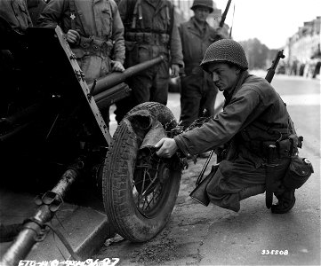 SC 335508 - Pfc. Joseph A. Calvello of New York City, N.Y., examines the sponge rubber interior of a Russian tire found on a 4.5 cm. anti-tank gun left behind by the retreating Germans in France. photo