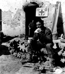 SC 374848 - At an aid station, L/Cpl. Aryeh Uri, from Jerusalem, Palestine, a squad leader in the Jewish Inf. Brigade, eats some matzo and tea after having been treated for a light wound. 30 March, 1945. photo