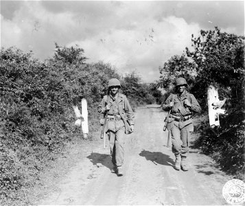 SC 270588 - S/Sgt. Robert Troxler, left, of Elson College, N.D., and Pvt. Charles Forkas, right, of Rutland, Vt., both members of an infantry unit, walk along a French road to rejoin their unit... photo