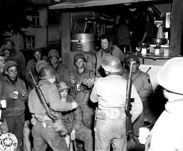 SC 195679 - Following chow at an Army rest camp in Belgium, GIs receive coffee and doughnuts from the Red Cross. 24 October, 1944. photo