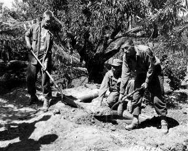 SC 184858 - L-R: Cpl. Elbert Pearson, So. Deerfield, Mass.; S/Sgt. Jack Boone, Montgomery, Ala., and Pvt. Charles Payne, Canton, Ohio, members of a Field Artillery unit near Niscemi, Sicily, cover their foxholes with empty shell boxes filled with dirt.