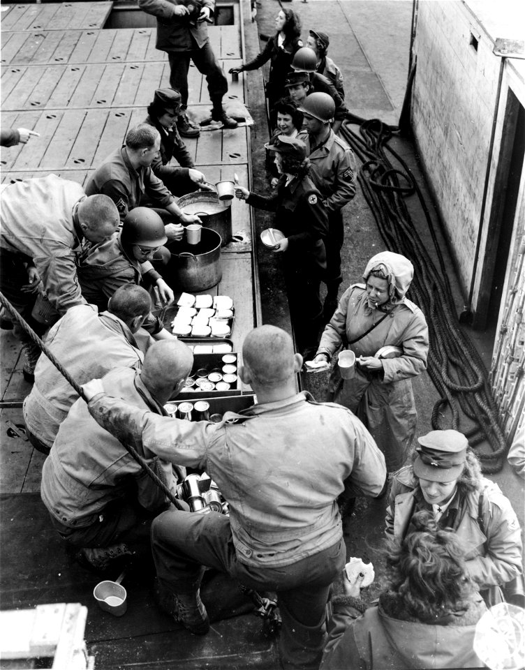 SC 329722 - This is a shot of the mixed ARC girls and GIs using and distributing delicious 'O' Rations on the #1 forward hatch of the Liberty Ship 'Edward W. Scripps'...