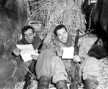 SC 199090 - T/4 Harry H. Hynes, Box 665, Antlers, Okla., and Pvt. Frank Benicasa, 470 Park Ave., Brooklyn, N.Y., right, read their mail in a barn near the front lines, in Rechrival. photo