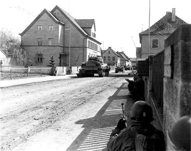 SC 335303 - Infantrymen crouch close to buildings as tanks go down the streets of Konigshoffen routing out snipers. 8 April, 1945. photo