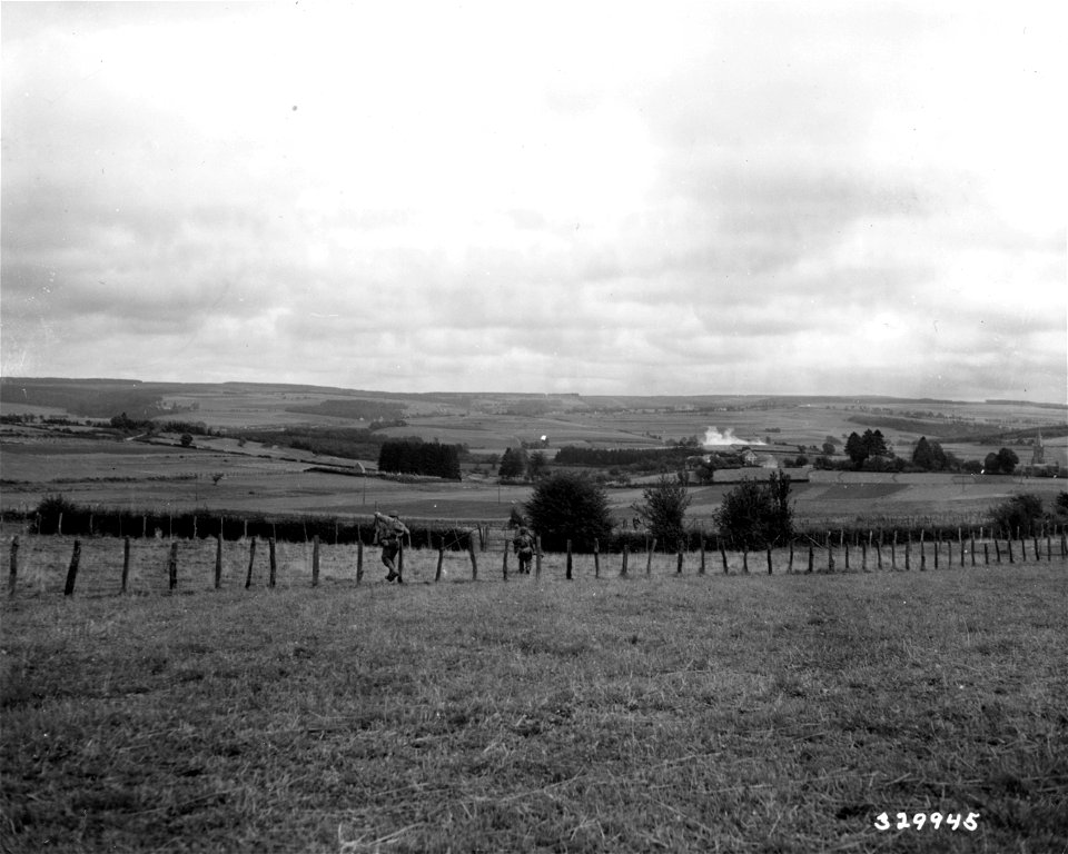 SC 329945 - Infantrymen advance cross country over gently rolling farmland toward Hatrival, Belgium.