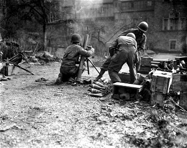 SC 364331 - Mortar team of the 99th Infantry Division, U.S. First Army, prepares to fire 81mm mortar shell to halt advance of enemy patrol in woods between American-held Ariendorf, and Germany-held Honningen.
